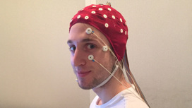Соавтор исследования Кристофер Мазурек (Christopher Y. Mazurek) в шлеме для считывания мозговой активности. К его лицу присоединены электроды для детекции движений глаз.