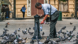 Мужчина набирает питьевую воду в фонтанчике во время аномальной жары в Кракове (Польша) 21 июня 2021 года.