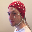 Соавтор исследования Кристофер Мазурек (Christopher Y. Mazurek) в шлеме для считывания мозговой активности. К его лицу присоединены электроды для детекции движений глаз.